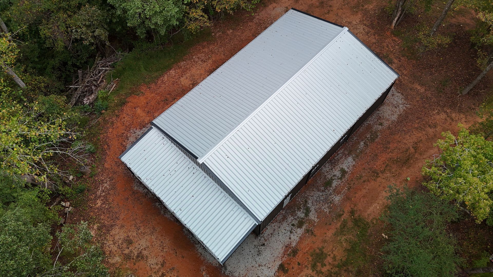 Aerial view of a metal-roofed building in a wooded area.