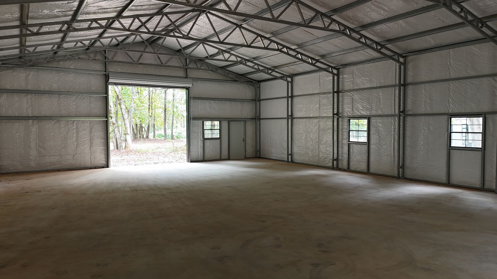 Empty metal warehouse interior with concrete floor and open doorway.