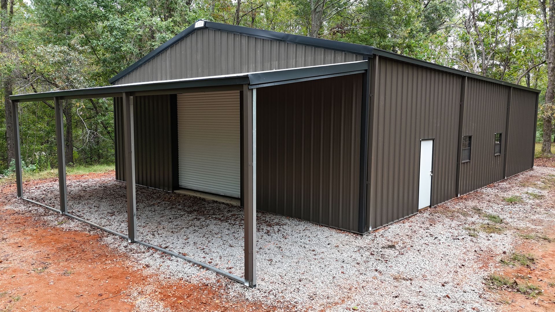 Brown metal storage shed with a covered porch, set on gravel.