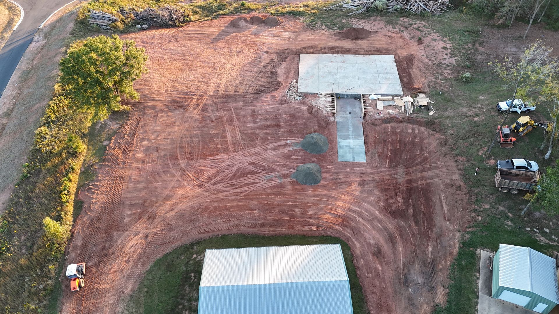 Aerial view of construction site with a building, dirt, and equipment.