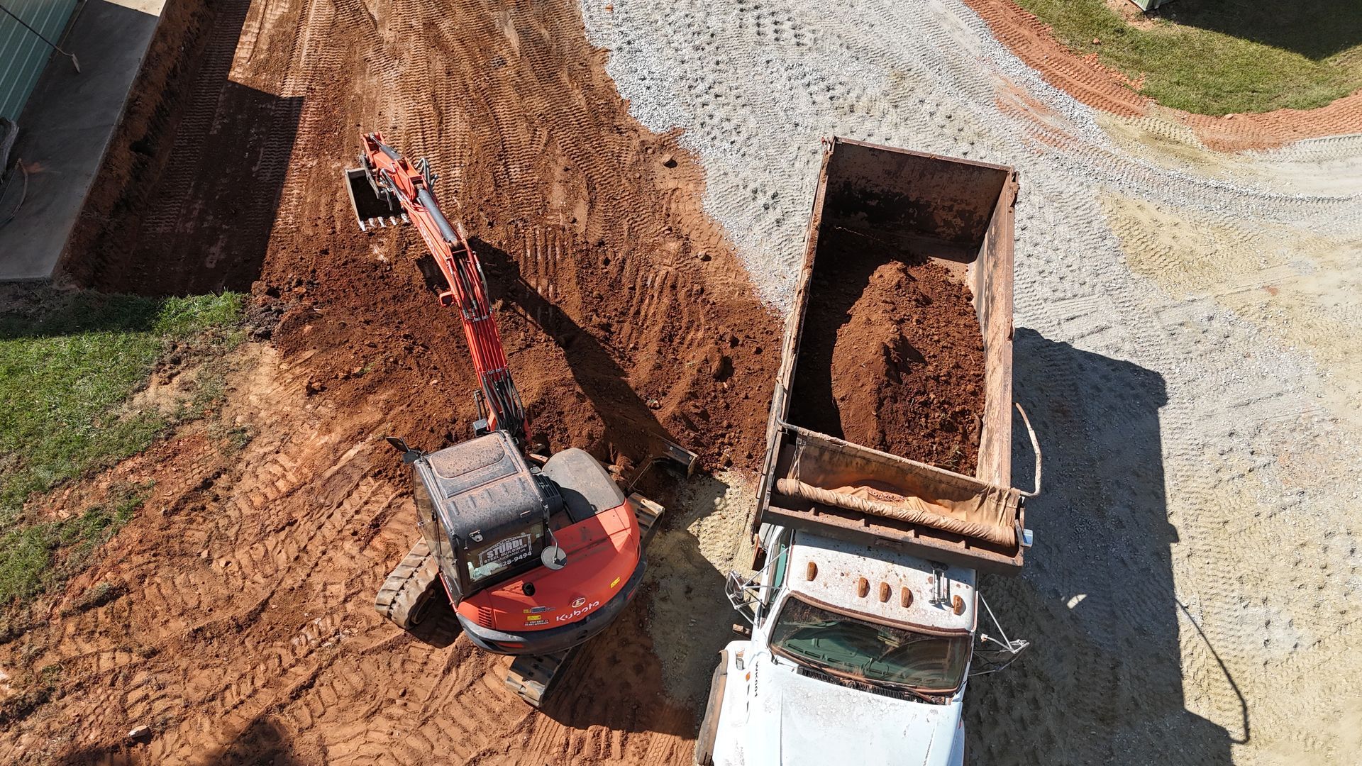 An excavator loading a dump truck with dirt on a construction site.