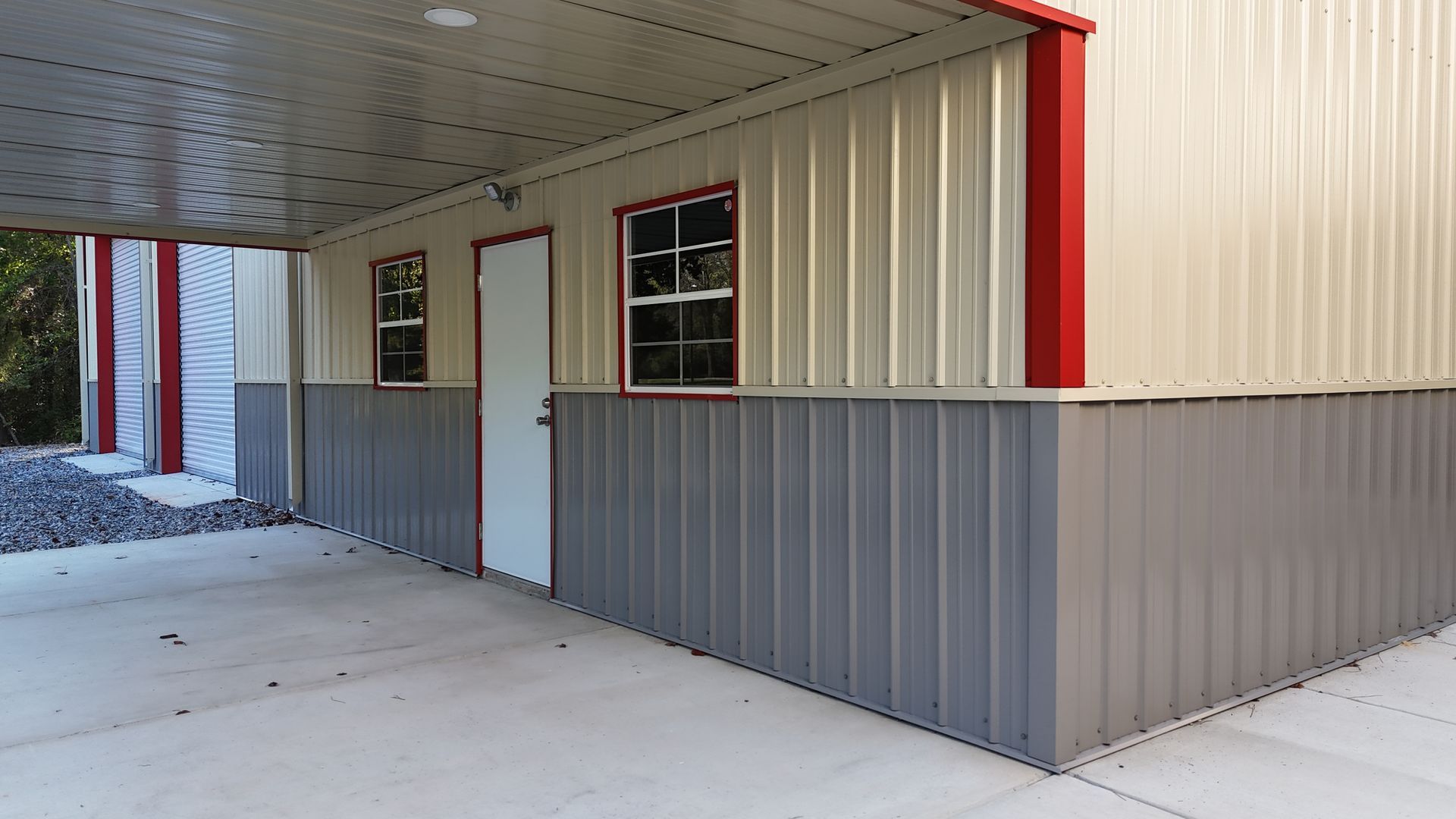 Metal building with tan and gray walls, red trim, and concrete flooring.