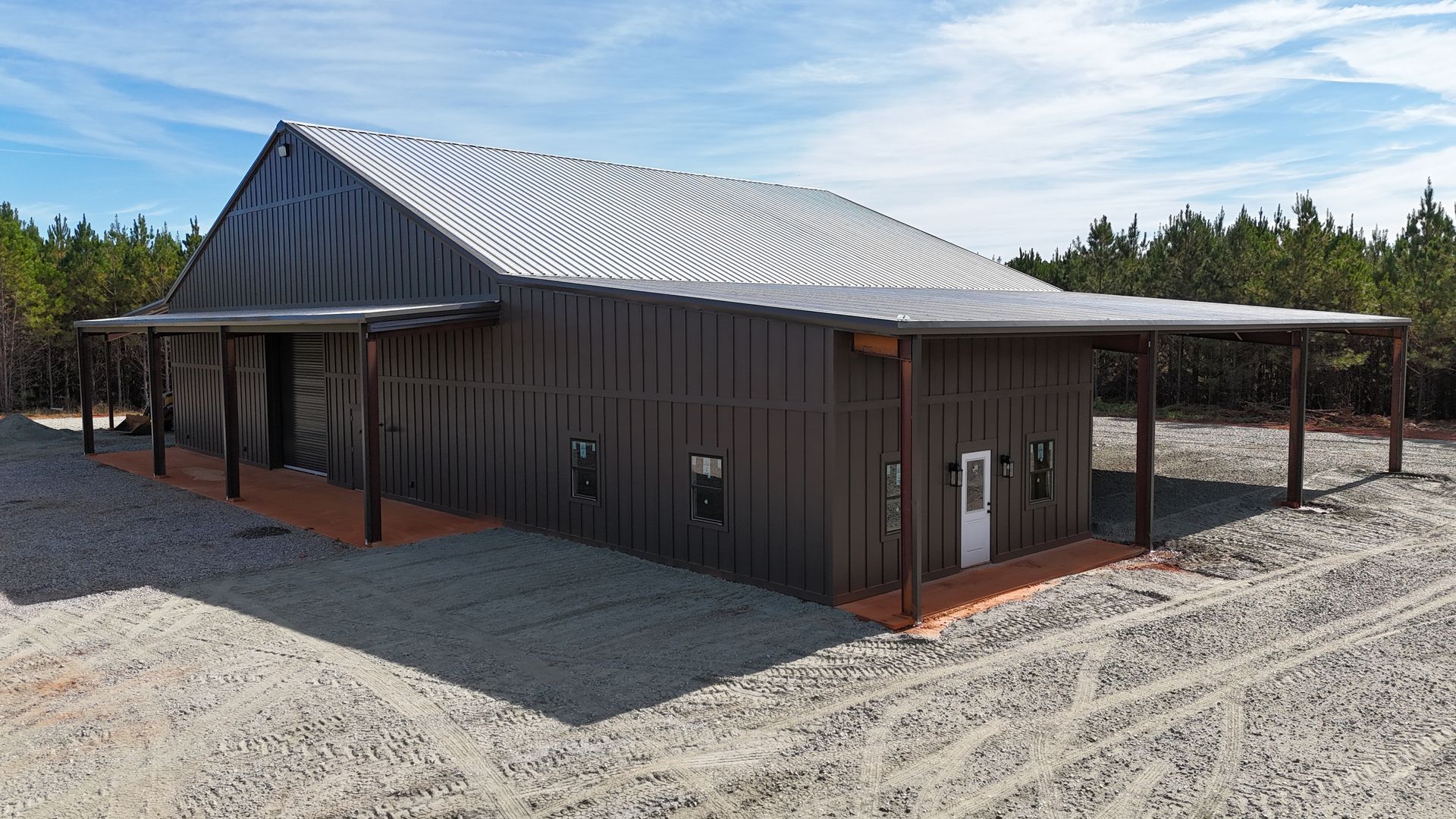 Brown metal barn with a gray corrugated metal roof and a covered porch.