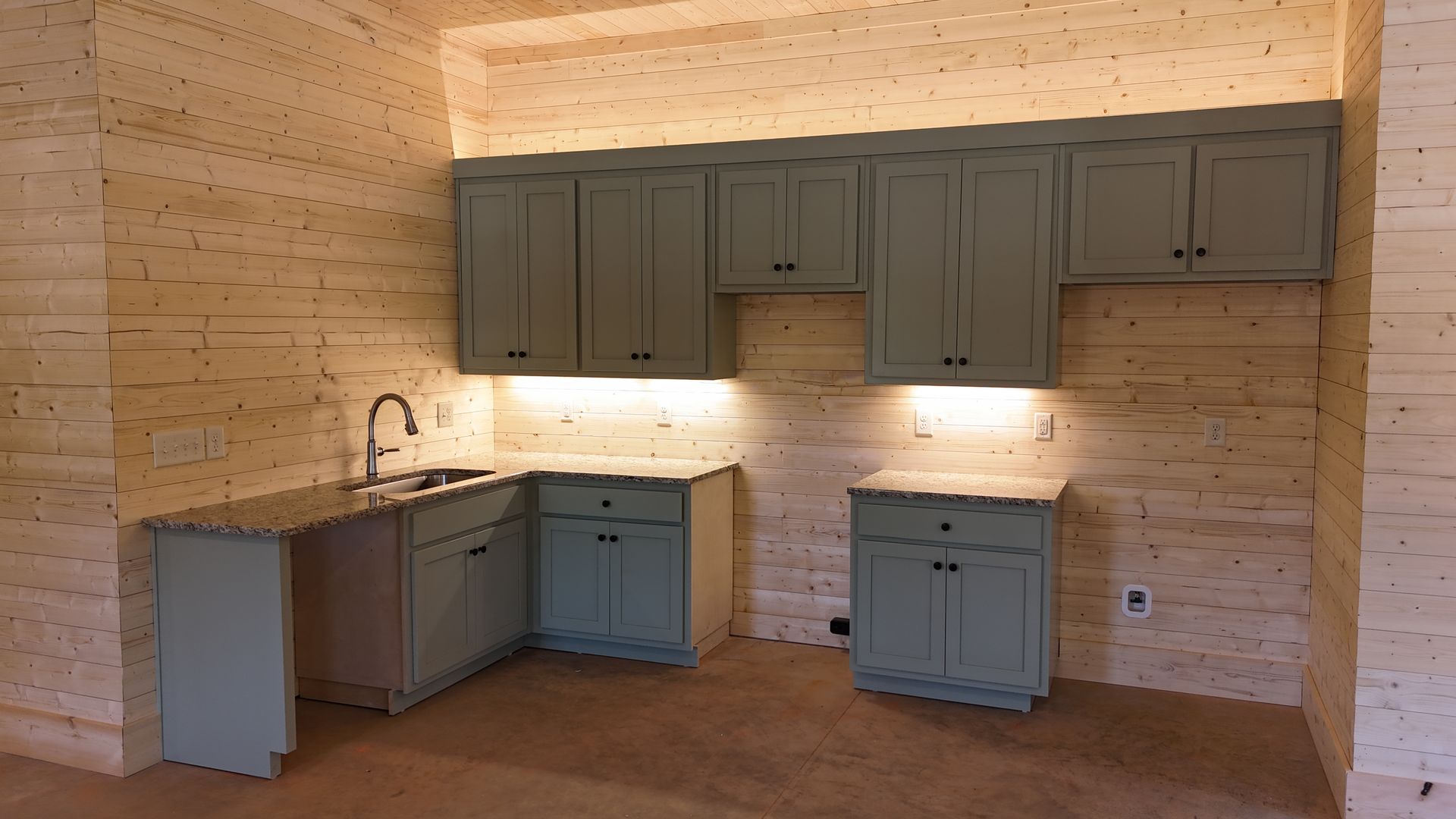 A small kitchen with light blue cabinets against a layered tan wall.