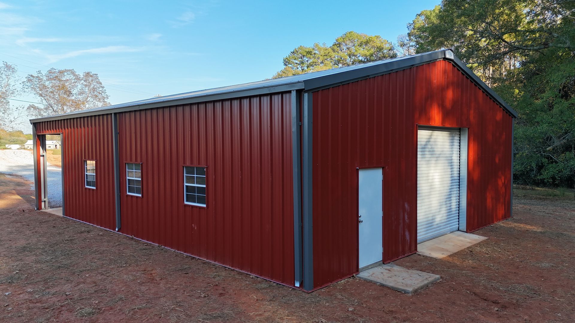Red metal storage building with gray trim and doors against a blue sky.