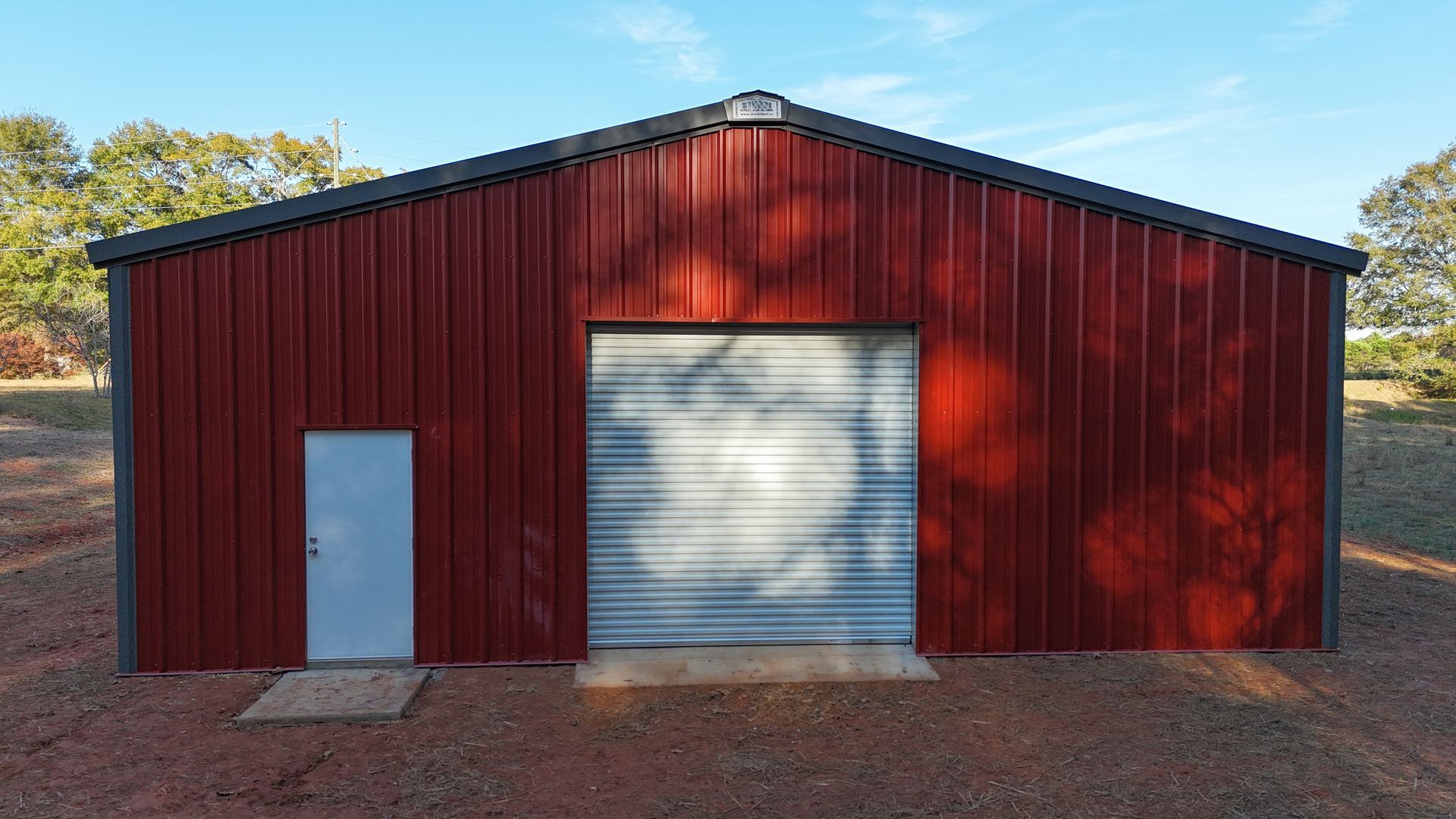 Red metal storage building with gray door and garage door.