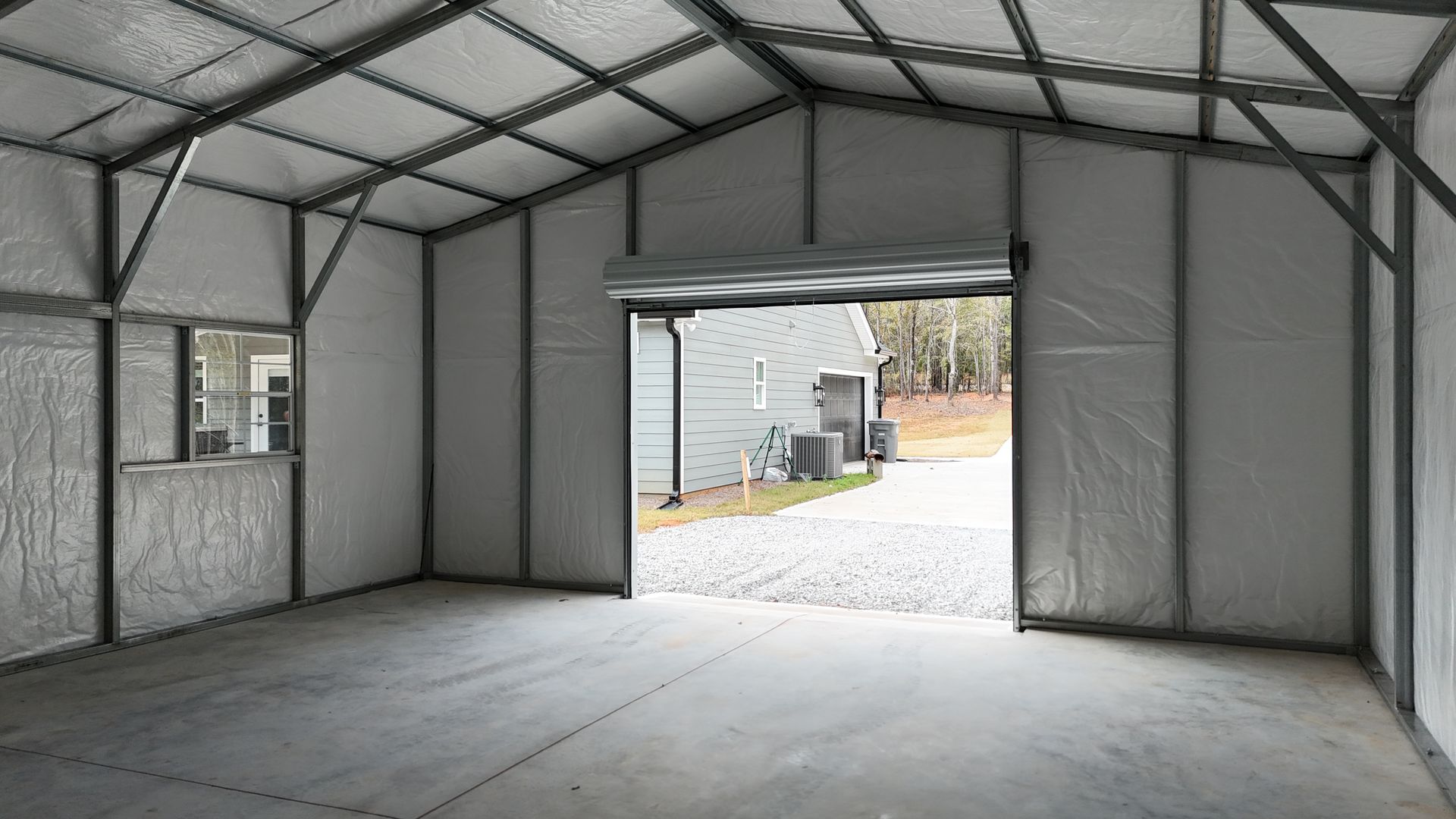 Interior of a metal building with a roll-up door open to the outside, concrete floor.