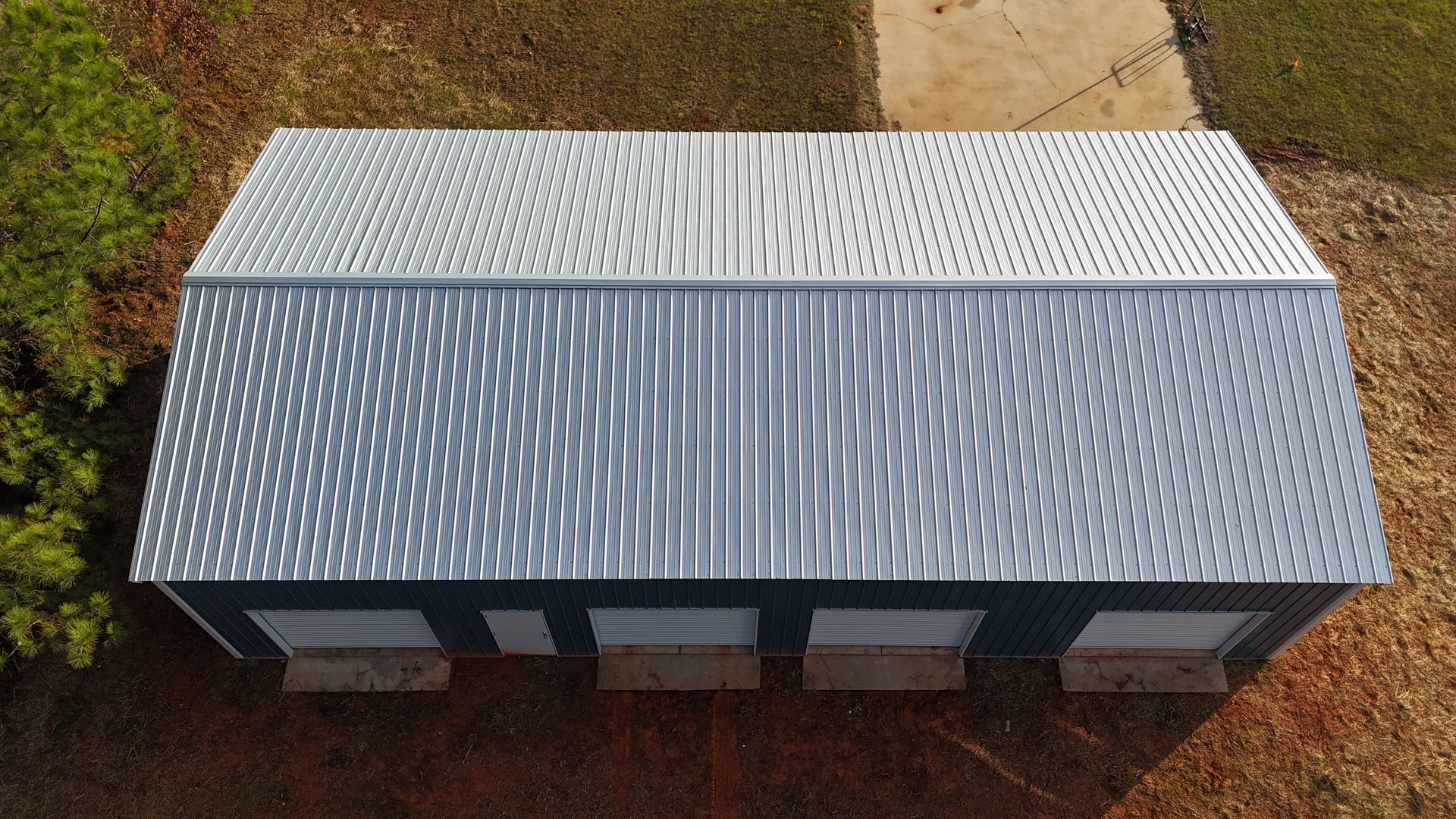 Overhead view of a metal building with a corrugated silver roof and blue walls.