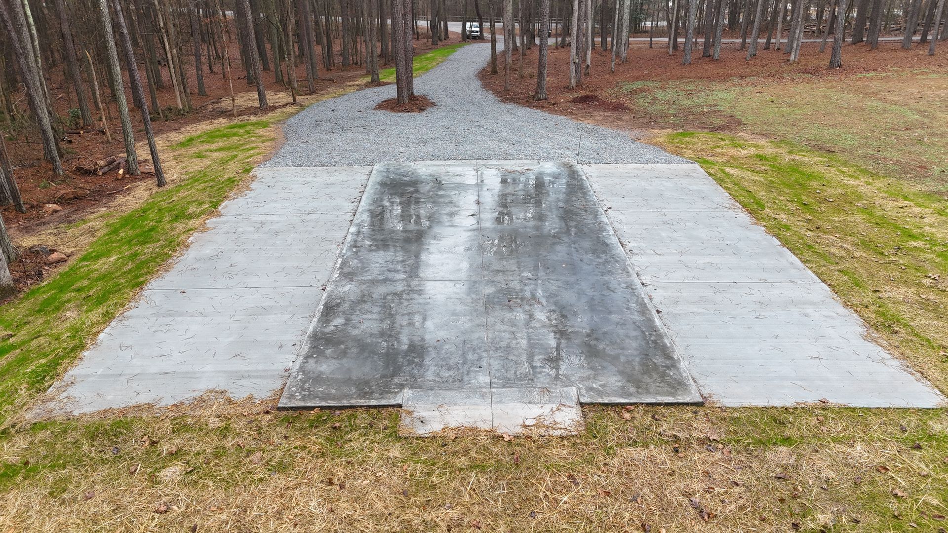 Concrete slab and gravel path in a wooded area.
