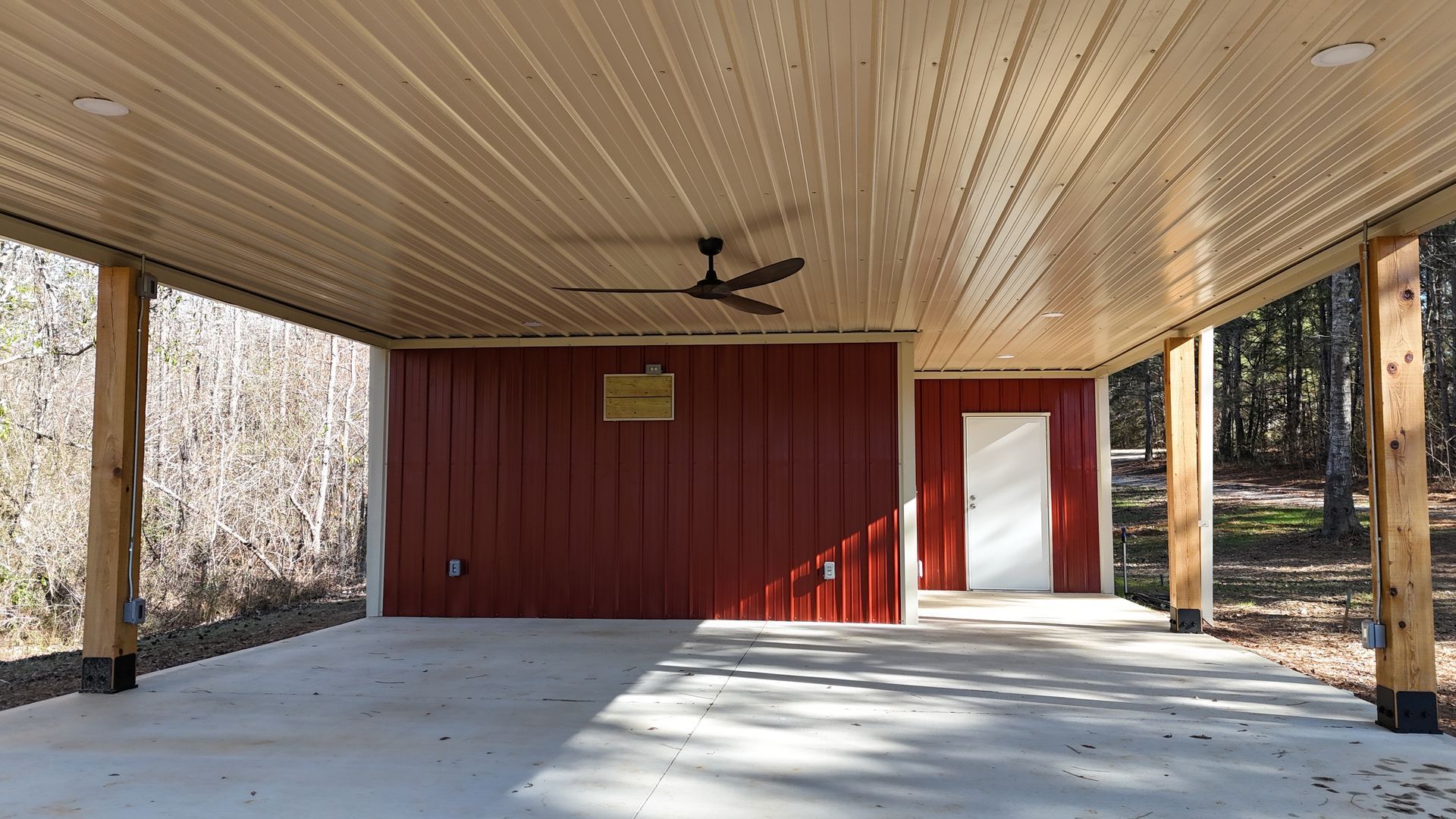 Covered outdoor space with red walls, concrete floor, tan ceiling, and ceiling fan.