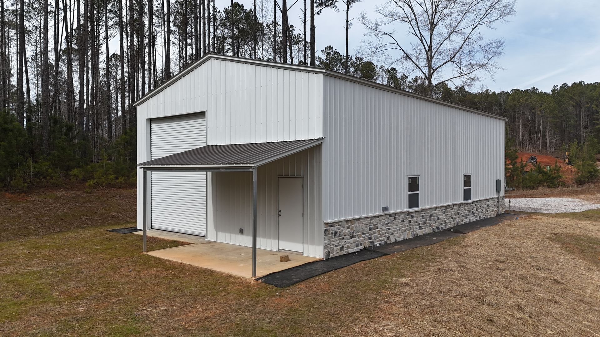 White metal building with a stone base and attached awning.