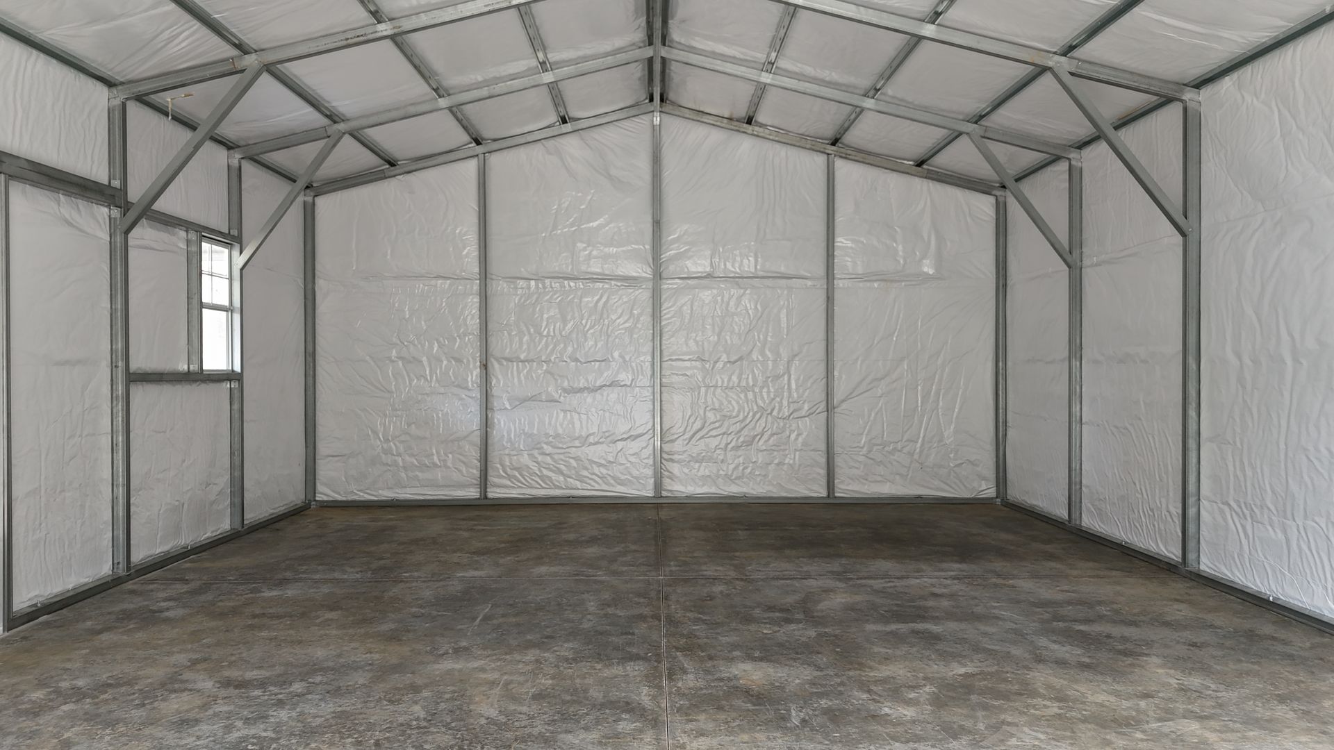Interior of a metal building with reflective insulation on walls and ceiling, metal framing, and a concrete floor.
