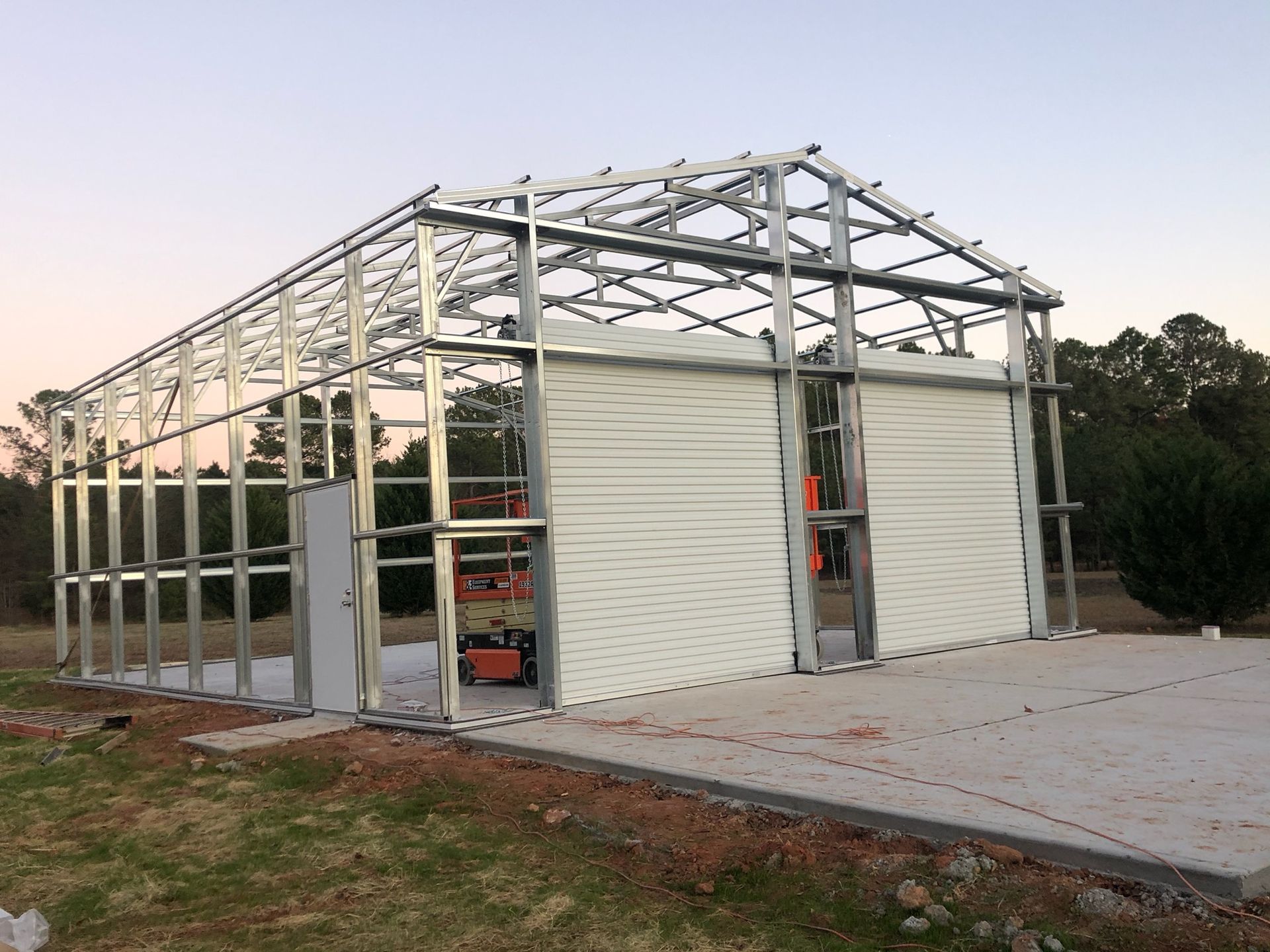 A large metal building is being built in a field.