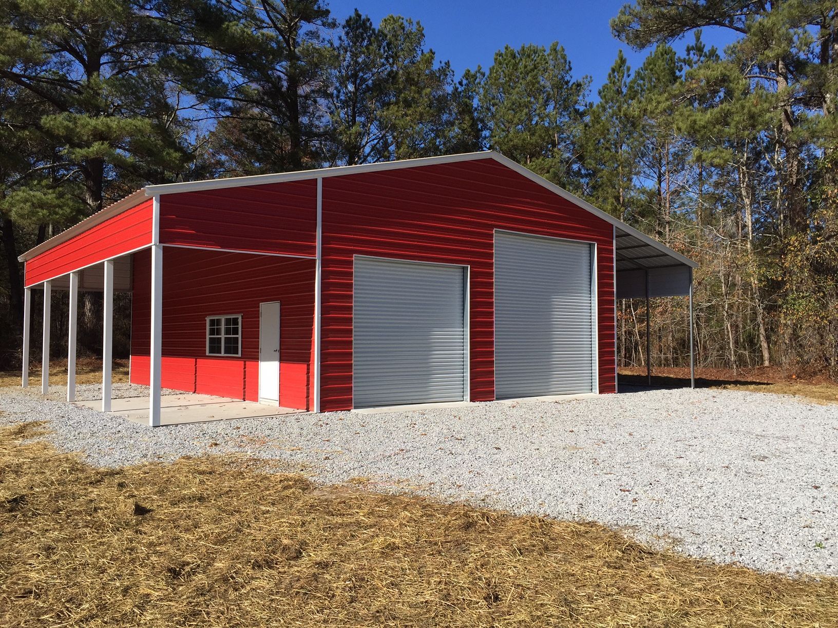 A red garage with a canopy is sitting on top of a gravel road.