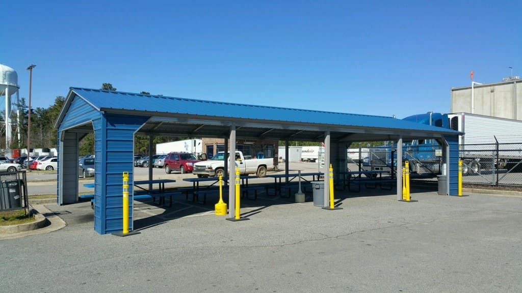 A blue shelter with a blue roof and yellow poles in a parking lot.