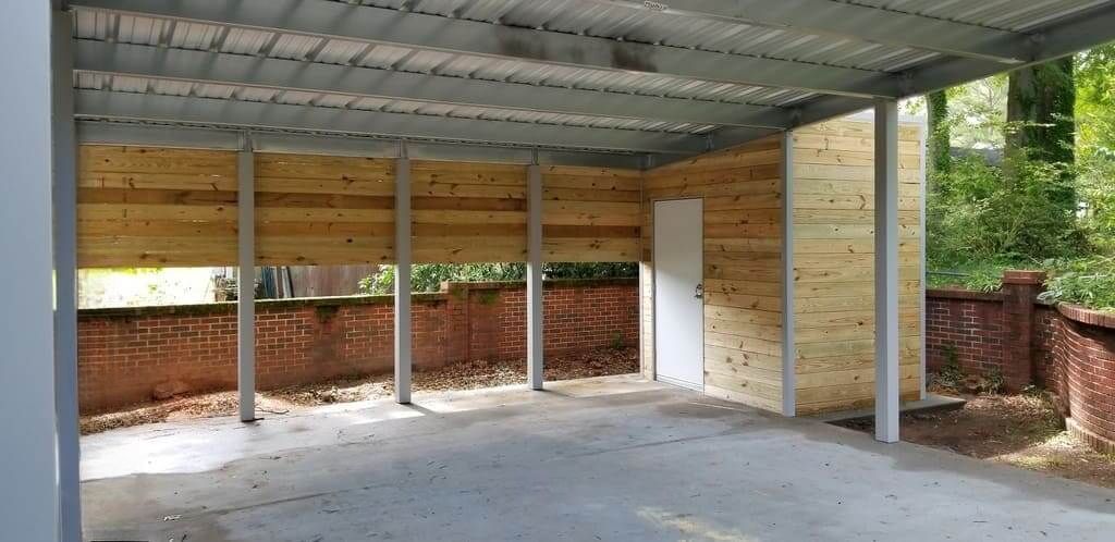 A carport under construction with a brick wall in the background.