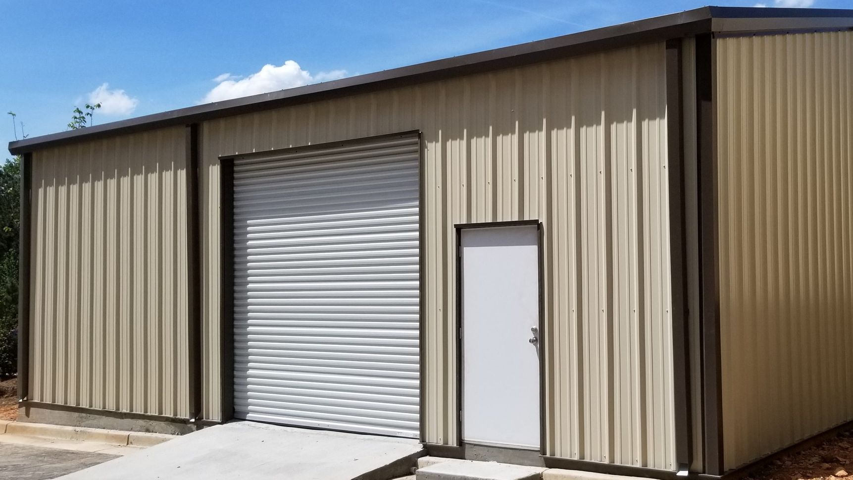 A large metal building with a garage door and a doorway.