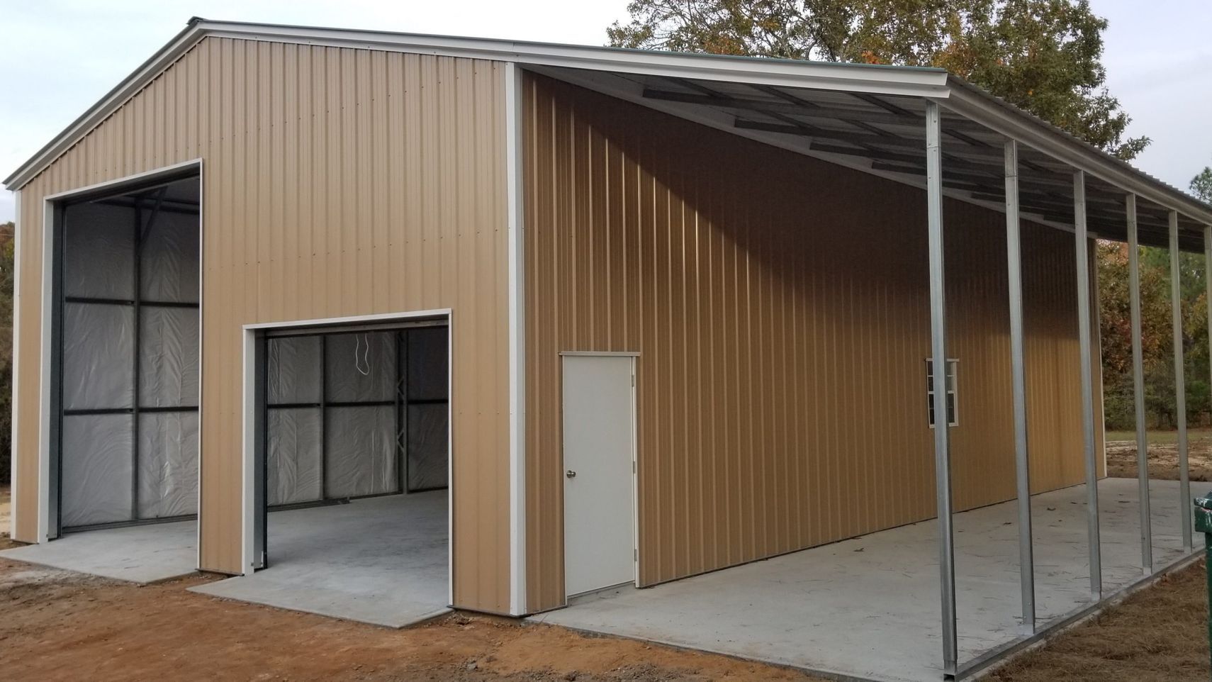 A large metal building with a covered parking lot in front of it.