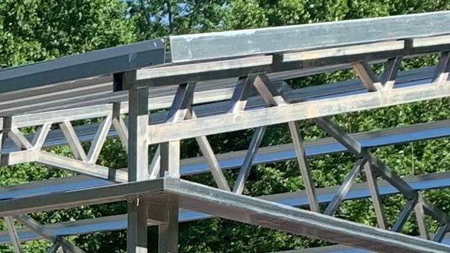 A close up of a metal structure with trees in the background.