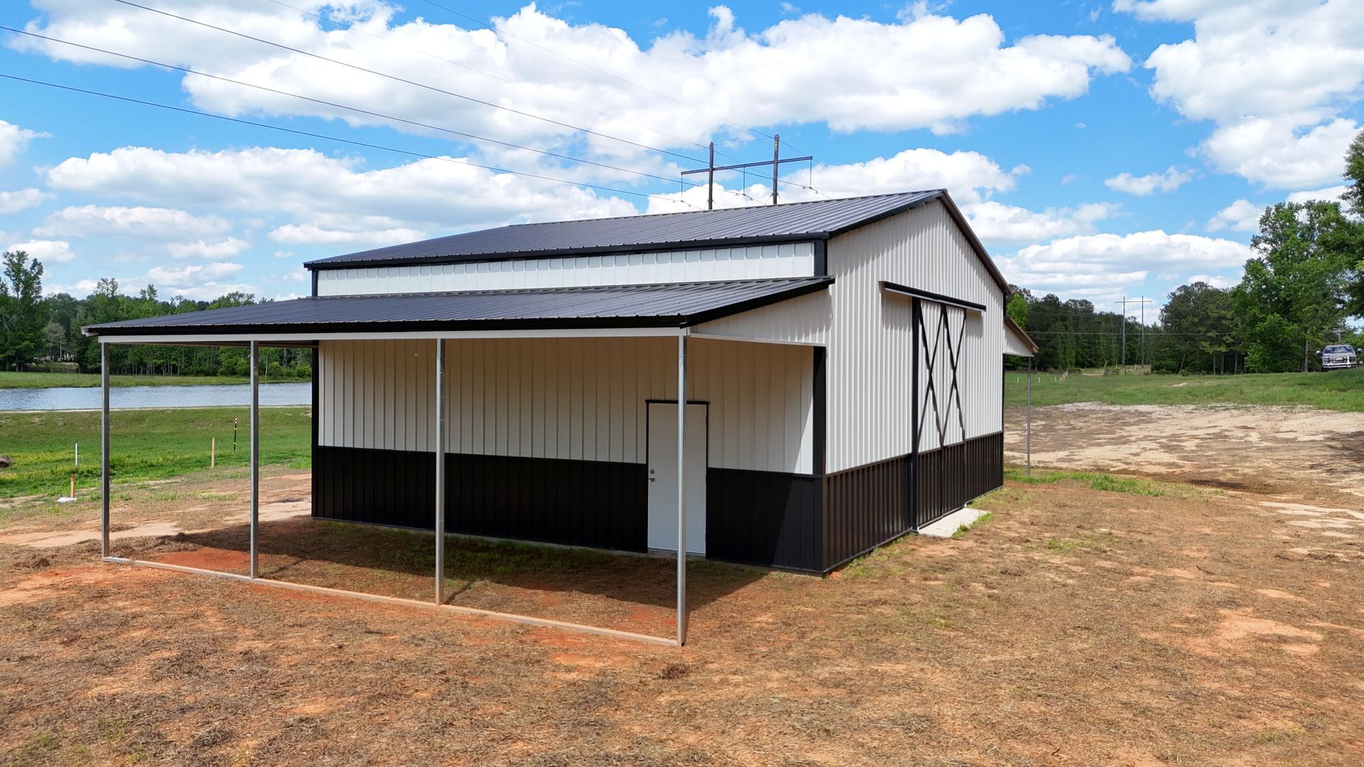 A white and black barn with a covered porch in a field.