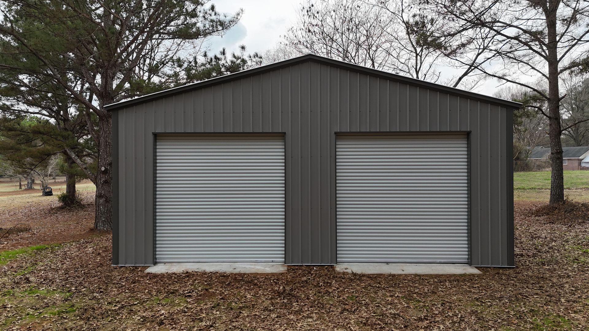 Gray metal garage with two doors in a grassy yard.