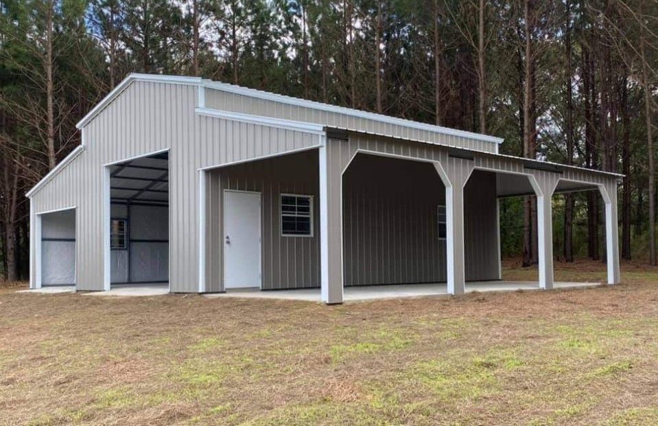 A large metal building with a porch in the middle of a field.