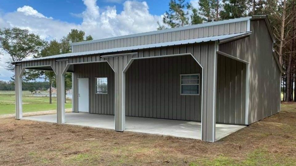 A gray metal building with a porch and trees in the background.