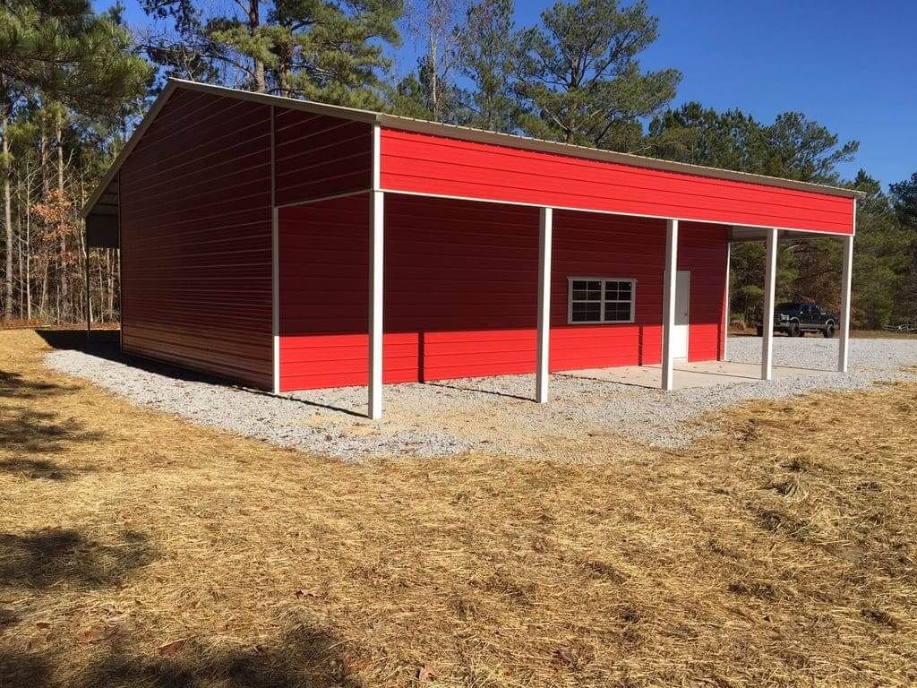 A red building with a porch is sitting in the middle of a field.