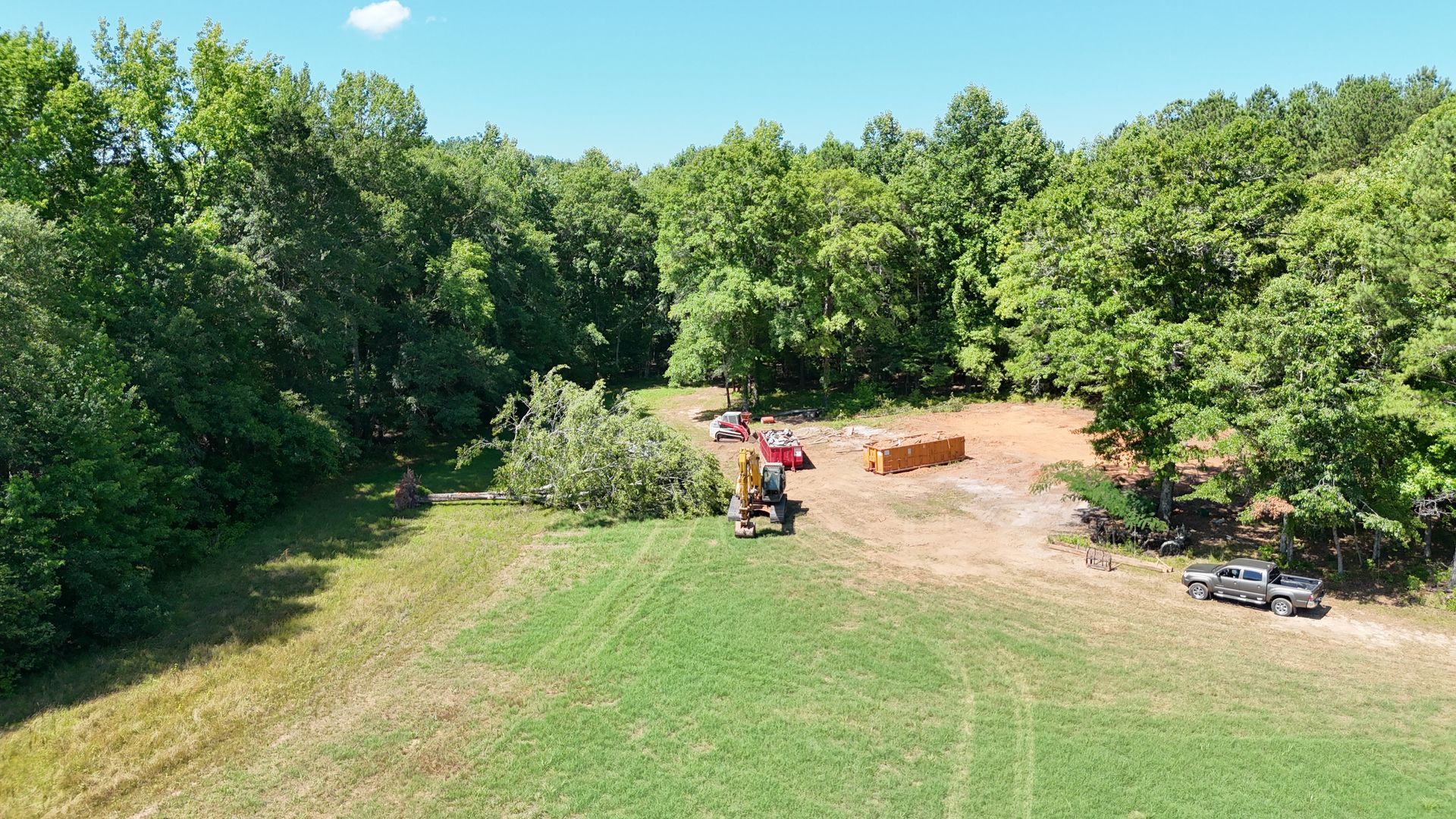 An aerial view of a tractor cutting trees in a field.