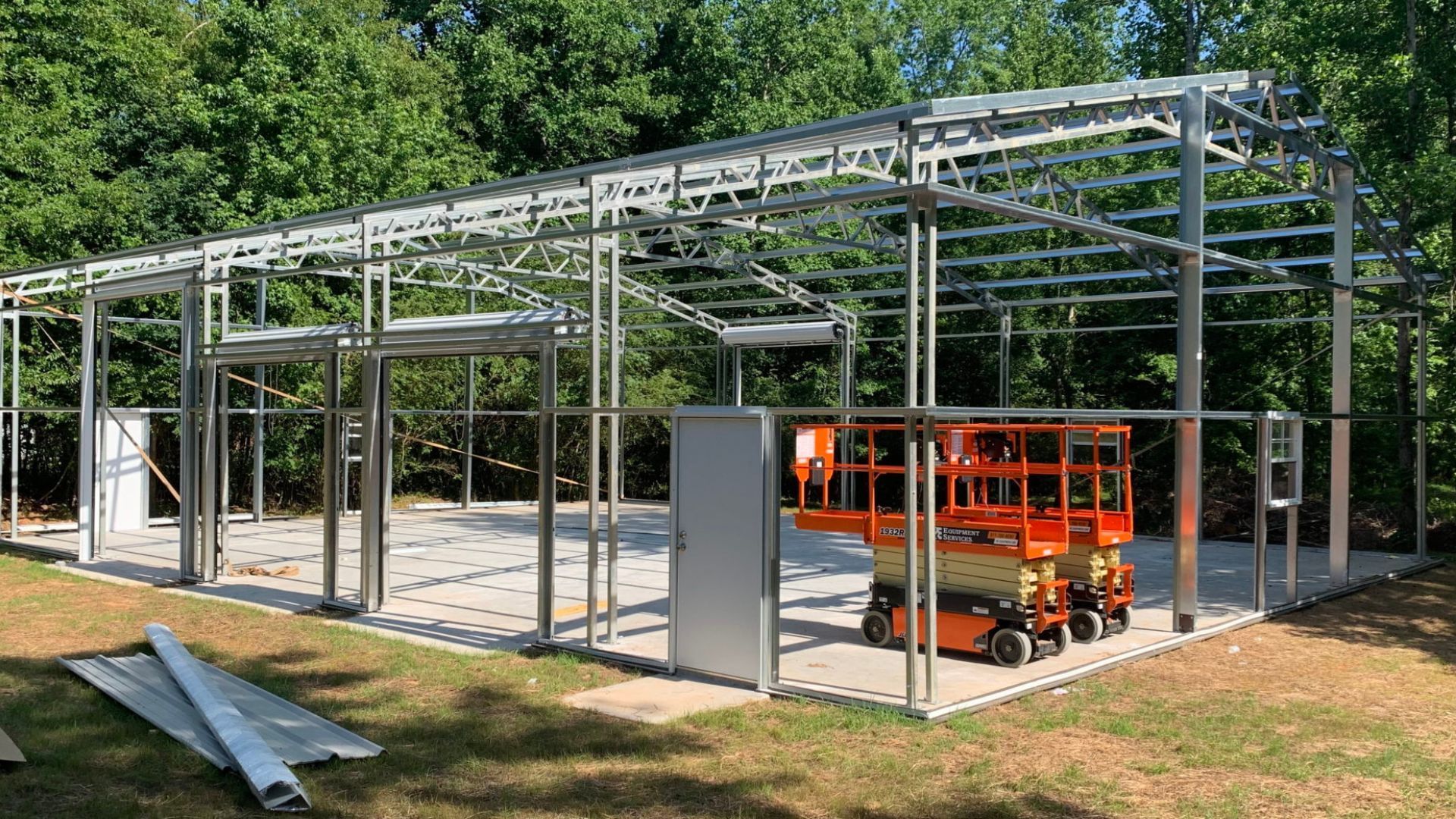 A large metal structure is being built with a scissor lift.