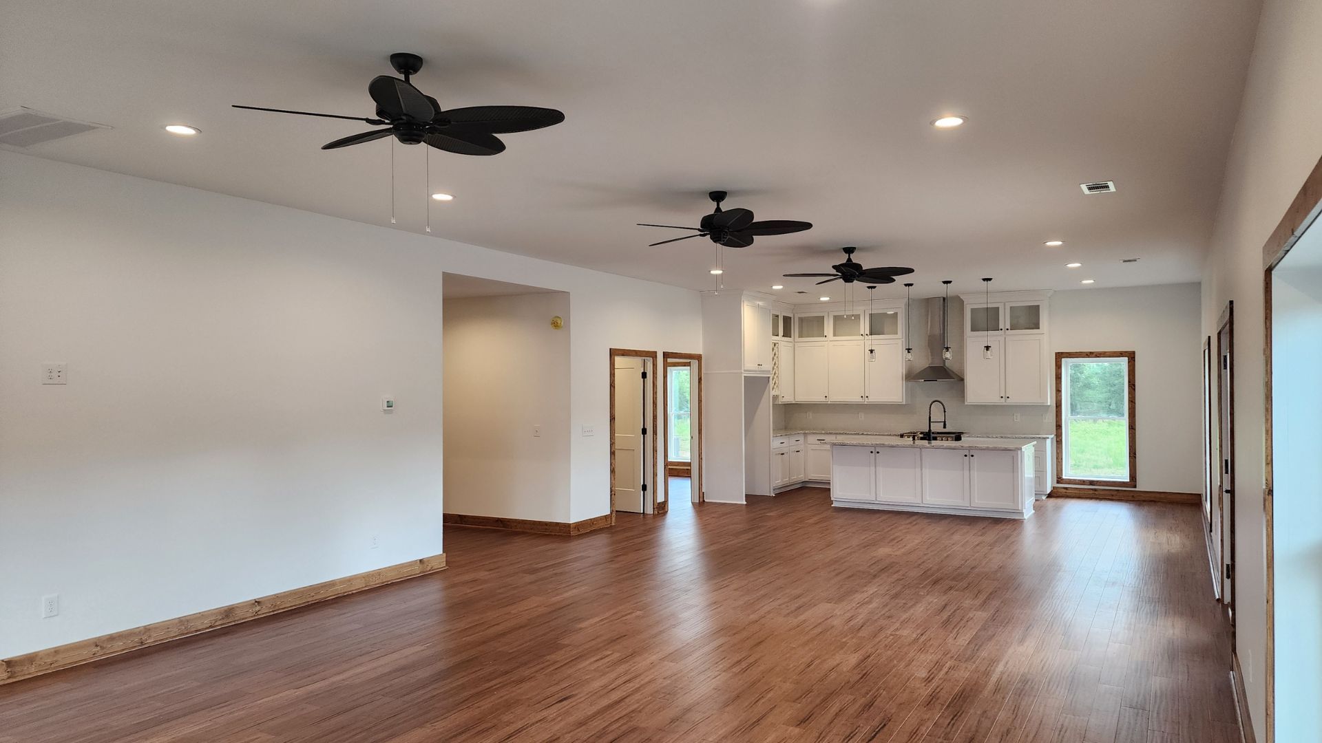 A large empty room with hardwood floors and ceiling fans.