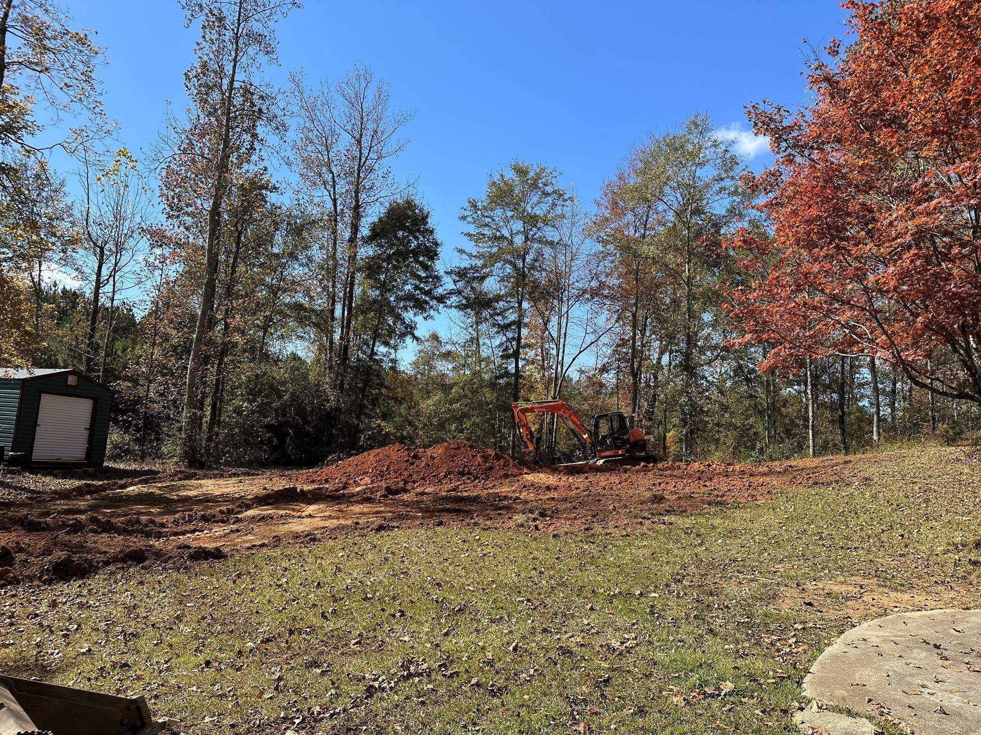 A bulldozer is moving dirt in a field with trees in the background.