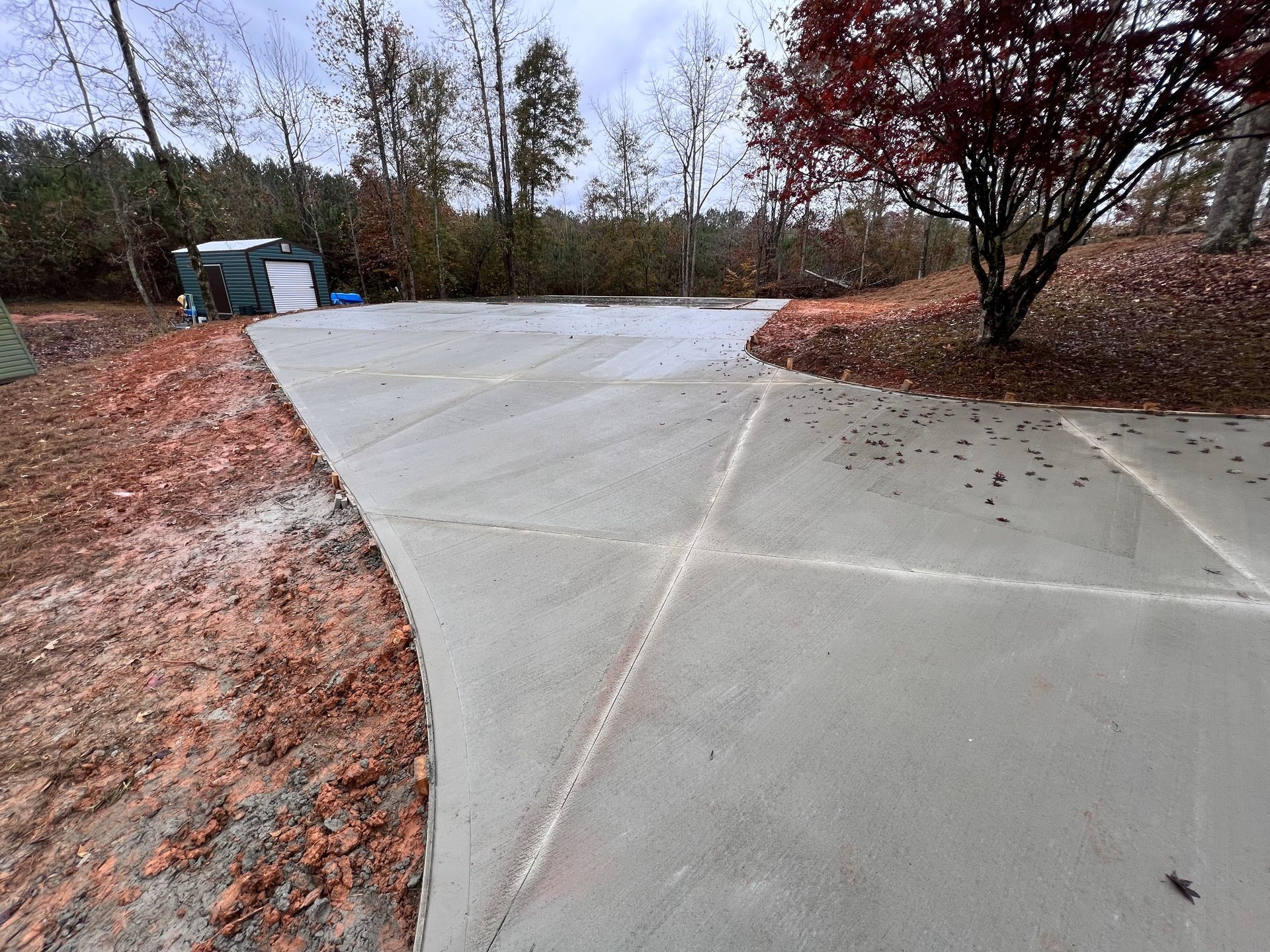 A concrete driveway with a tree in the background.