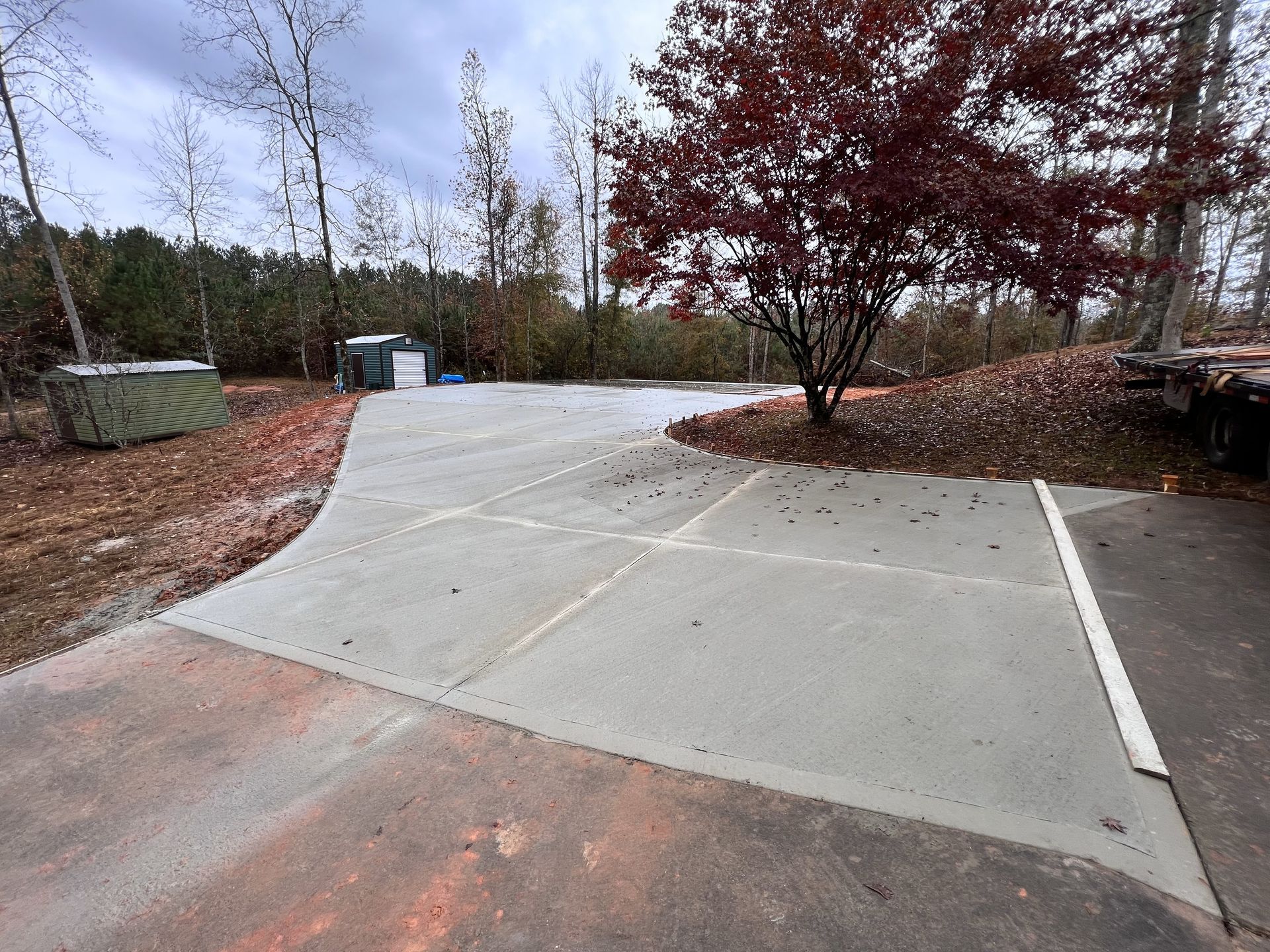 A concrete driveway with a tree in the middle of it.
