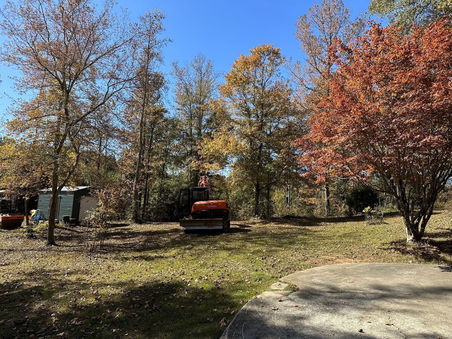 A tractor is parked in the middle of a field surrounded by trees.