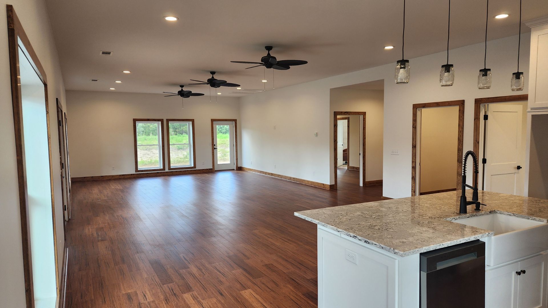 A large empty room with hardwood floors and a kitchen.