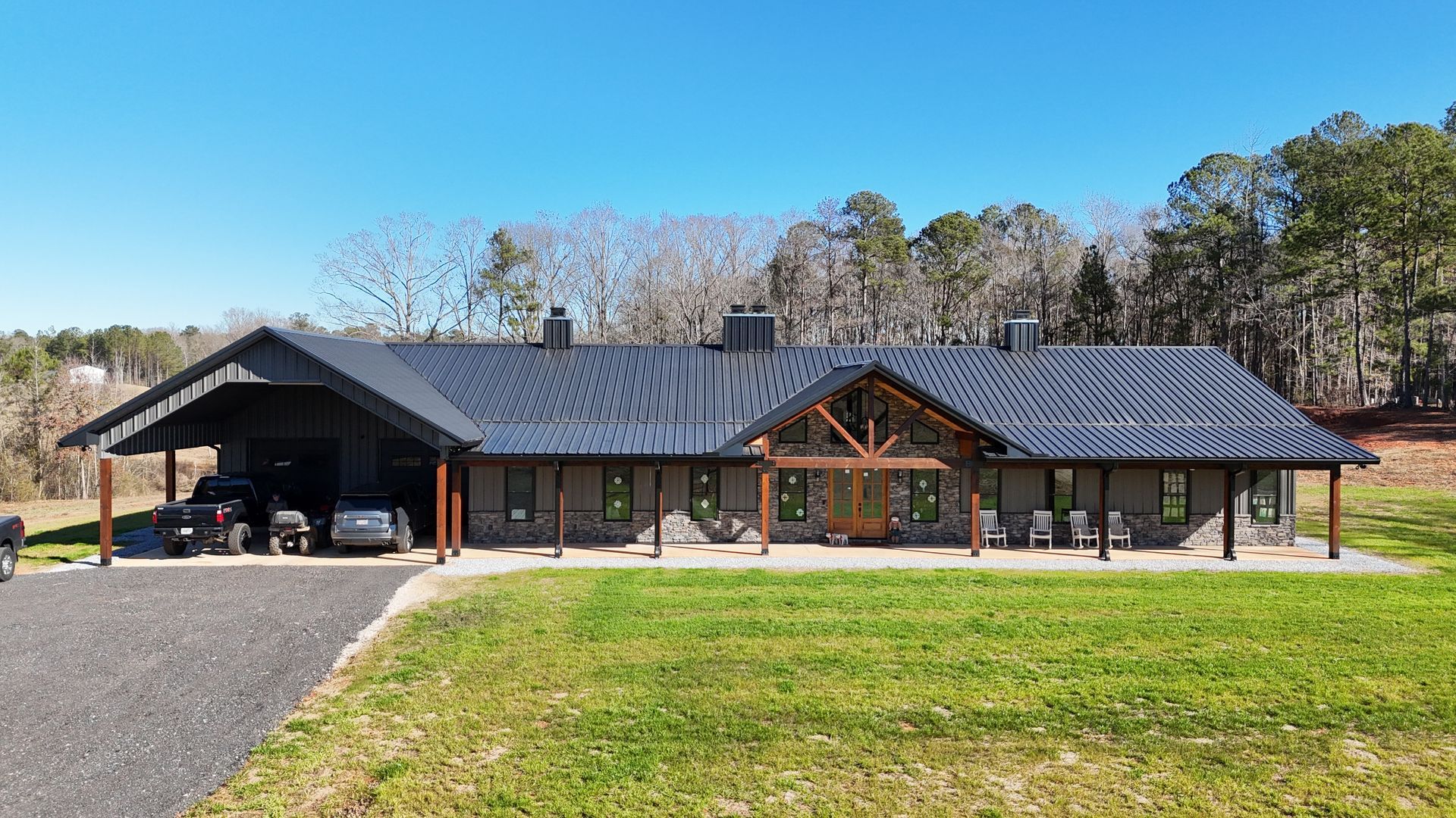 A large house with a black roof is sitting on top of a lush green field.