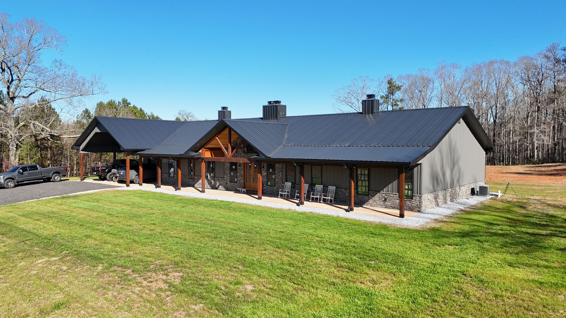 A large house with a black roof is sitting on top of a lush green field.