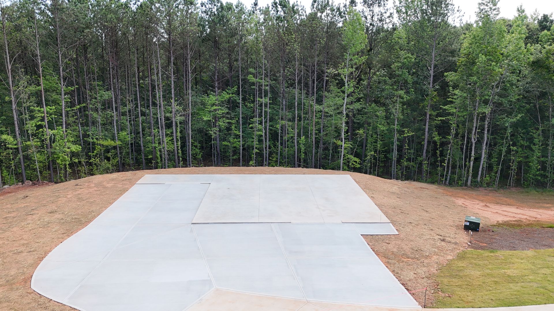 An aerial view of a concrete driveway with trees in the background.