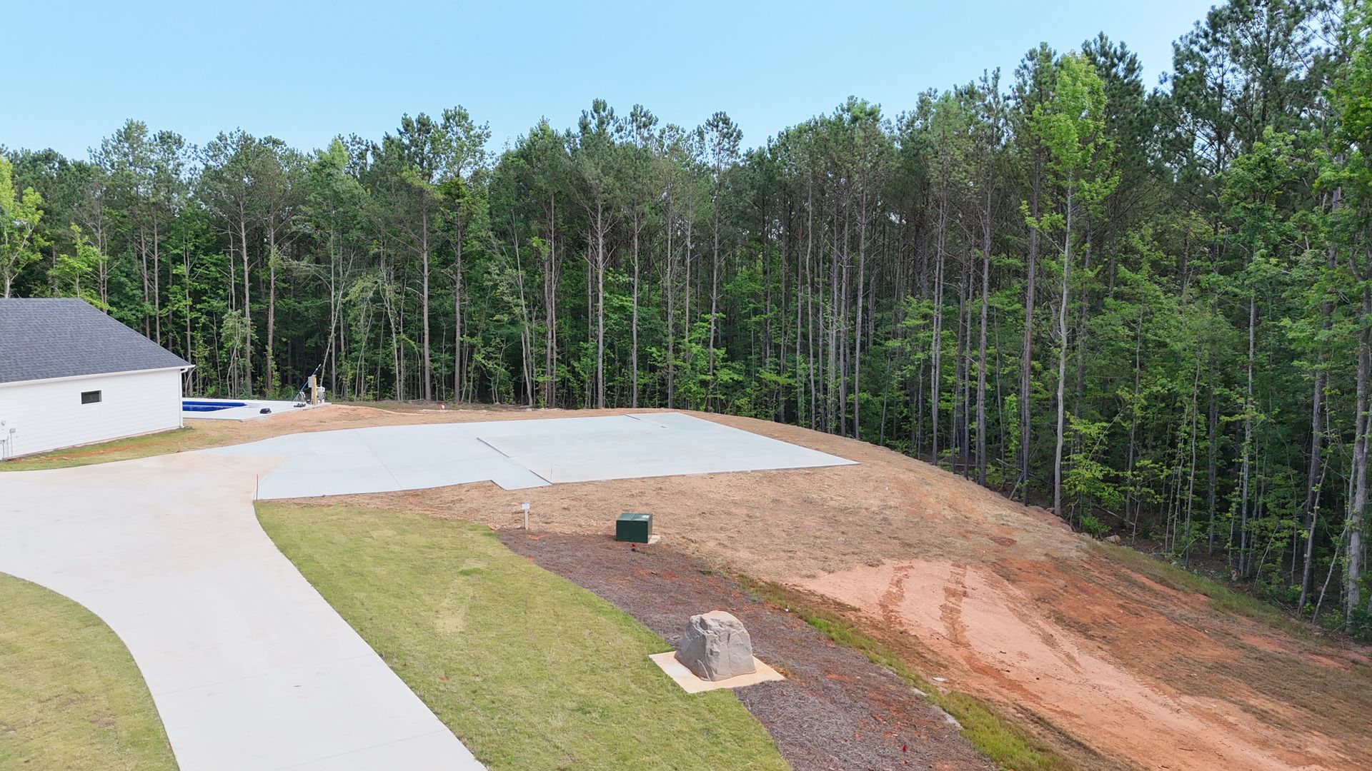 An aerial view of a house sitting on top of a dirt hill surrounded by trees.