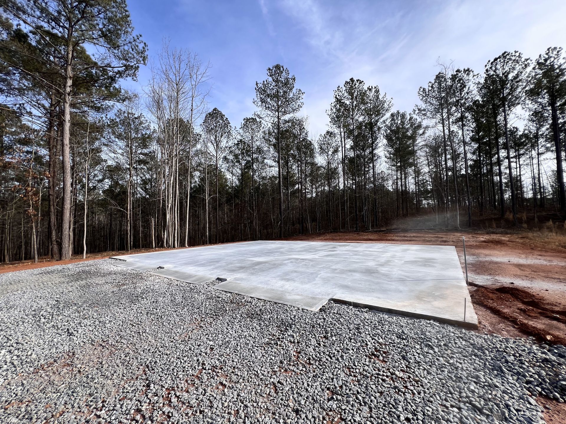 A gravel road with a concrete foundation in the middle of a forest.