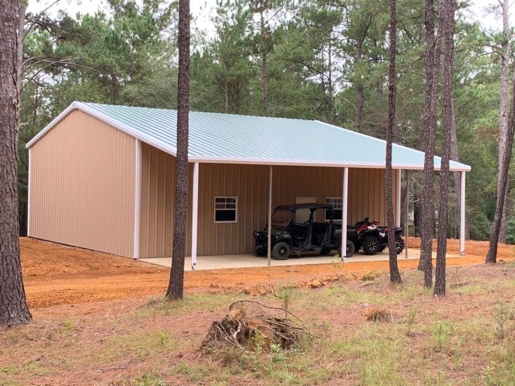 A metal building with a porch and two atvs parked inside of it.