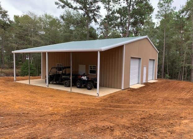 Two atvs are parked under a canopy in a garage.