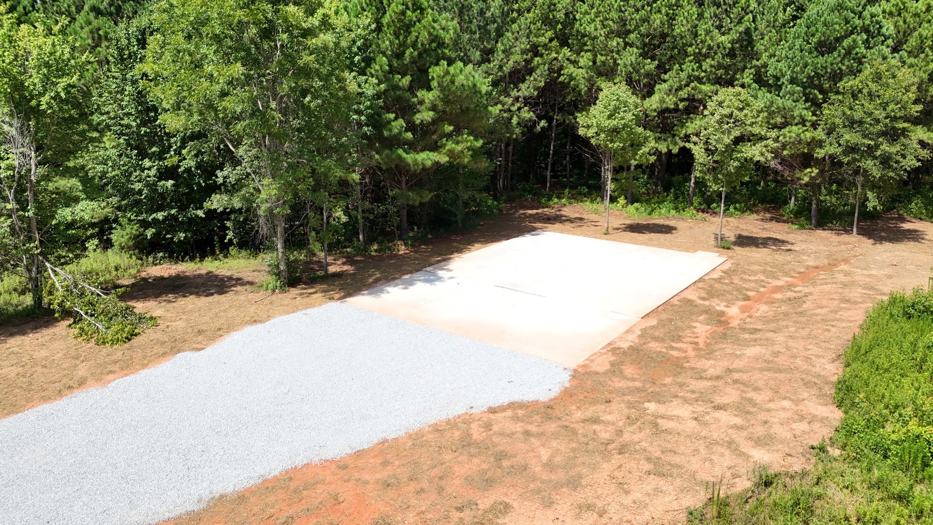 An aerial view of a dirt road in the middle of a forest.