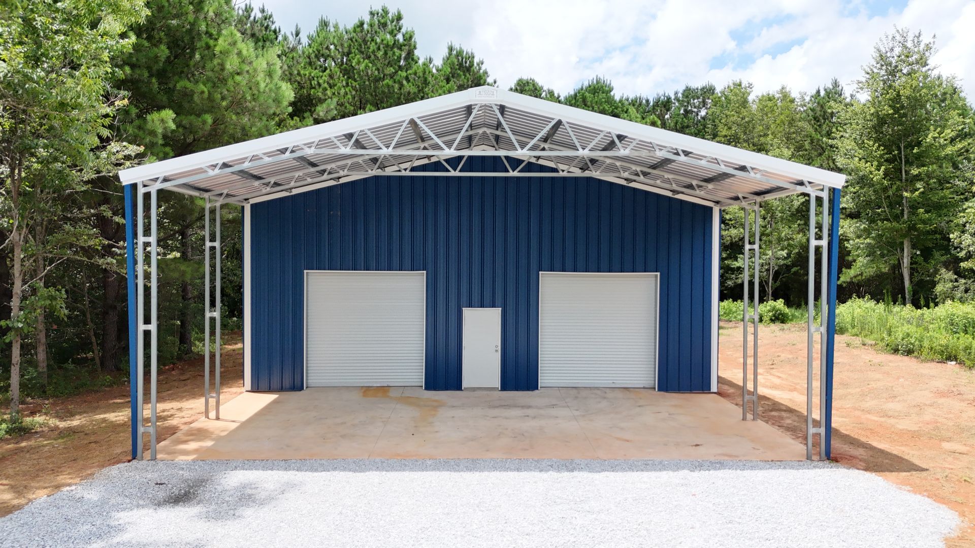 A large metal building with a black roof is sitting in the middle of a field.
