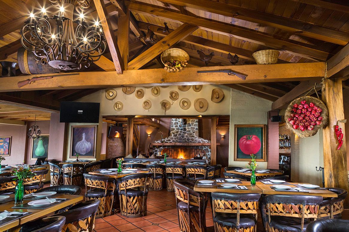 A large dining room with tables and chairs and a fireplace.