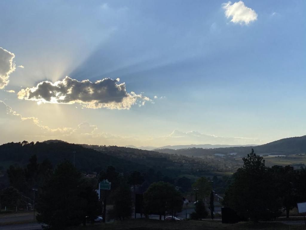 The sun is shining through the clouds over a valley