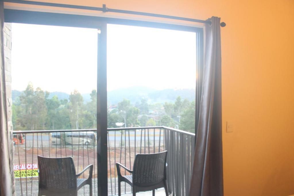 A room with a sliding glass door leading to a balcony with two chairs.
