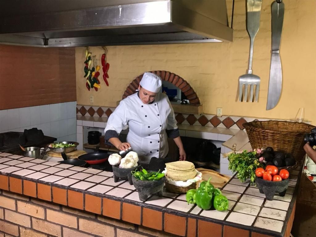 A chef is preparing food in a kitchen with a large fork on the wall.