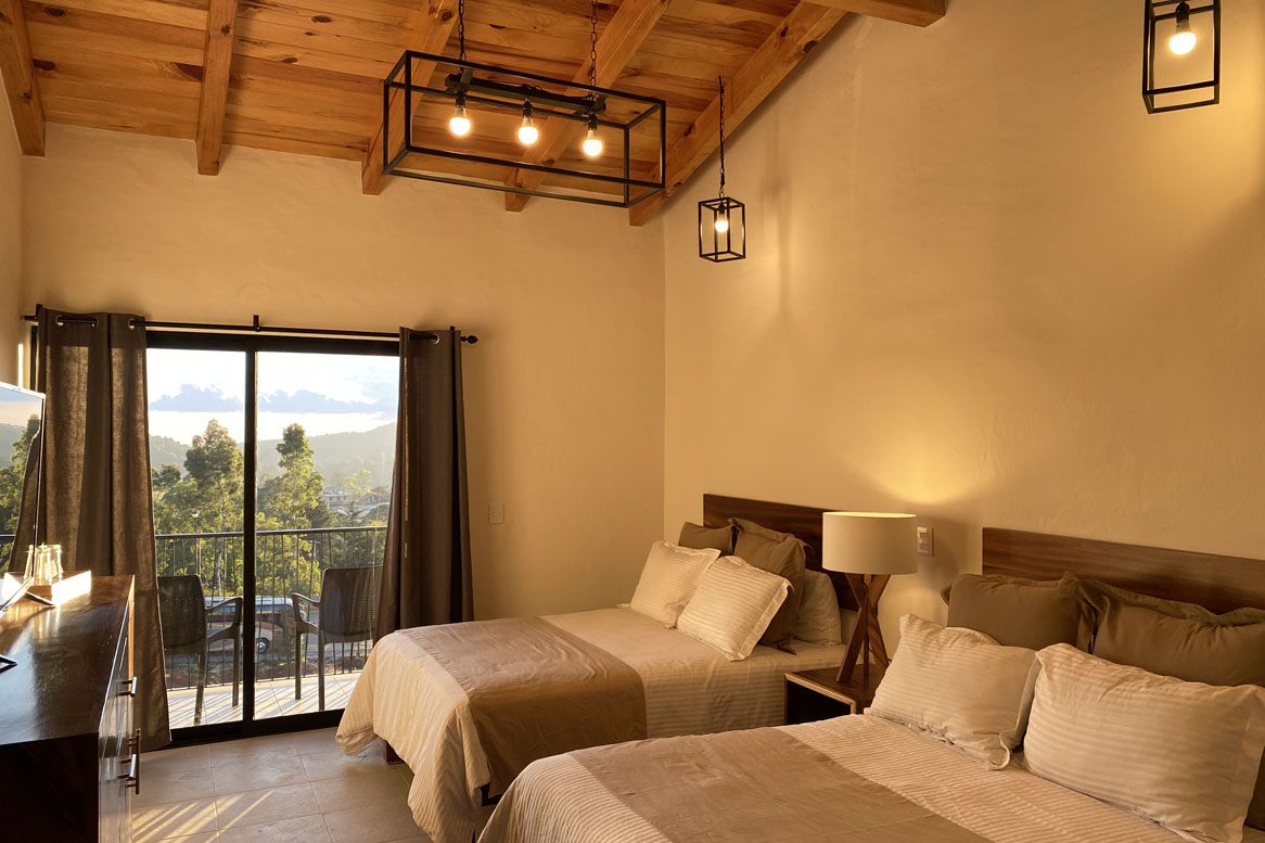 A hotel room with two beds and a sliding glass door.